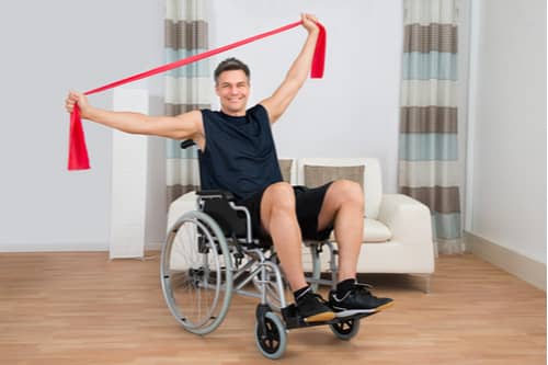 Man on wheelchair exercising with resistance band, Lehigh Acres spine injury treatment
