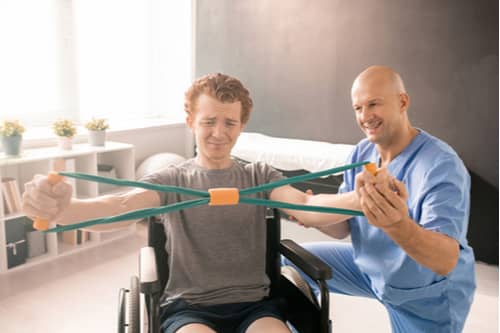 Pompano Beach spine injury treatment ​​physical therapist and young man in wheelchair