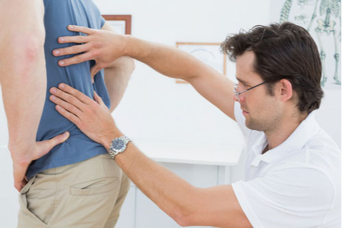 Davie herniated disc treatment, chiropractor examining man with back pain