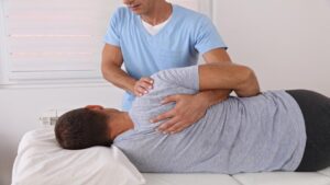 Male Chiropractor Adjusting the Back of His Patient