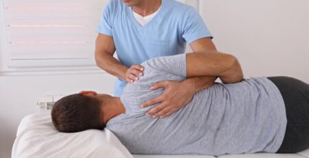 Male Chiropractor Adjusting the Back of His Patient